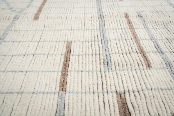 Close-up of a high-pile off-white rug featuring a grid pattern in thick taupe and light gray lines.