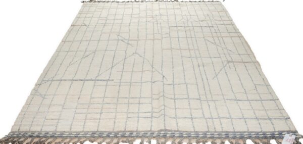 Off-white high-pile rug with blue-gray geometric grid pattern and gray tasseled fringe.