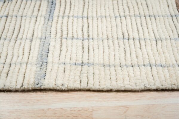 Thick shaggy cream and blue checkered rug texture resting on light wood flooring.