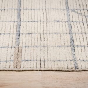 Close-up view of a chunky ivory rug with a sparse blue and tan grid design resting on light wood flooring.