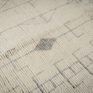 Textured cream rug with shaggy pile and a faint, irregular gray geometric pattern.