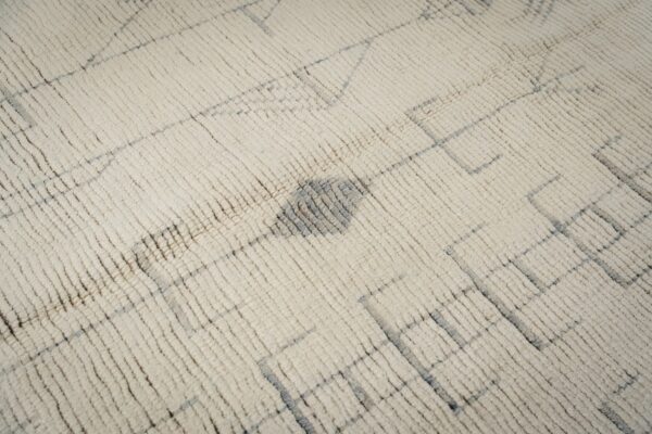 Textured cream rug with shaggy pile and a faint, irregular gray geometric pattern.