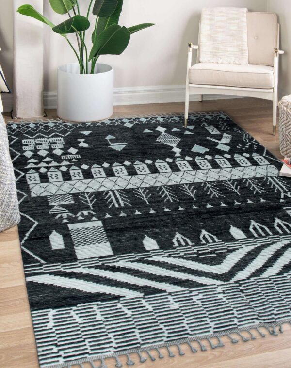 A black and pale blue geometric patterned rug covers light wood flooring near a white armchair.