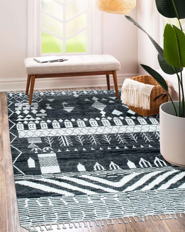 Black and white geometric rug on wood flooring next to a bench and large potted plant.