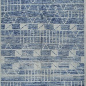 High-low pile rug in blue and white/gray with tribal geometric patterns and short fringed edges.