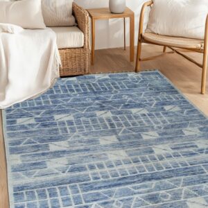 A faded blue geometric rug with tassels anchors a bright sitting area with wicker furniture.