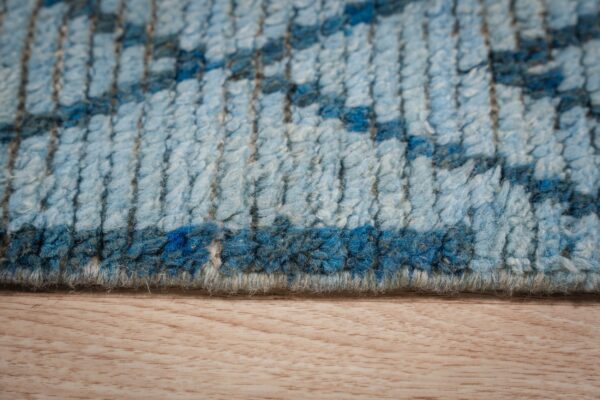 Textured high-pile rug in varying blues, displaying a geometric pattern on light wood flooring.