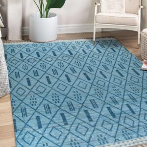 Textured blue flatweave rug with dark diamond patterns lies on hardwood floor near a plant and white chair.