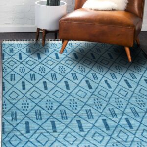 Blue geometric patterned rug on dark flooring beneath a caramel leather chair and potted plant.