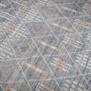 Textured blue and gray rug with white and peach abstract geometric patterns.