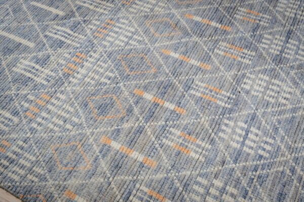 Textured blue and gray rug with white and peach abstract geometric patterns.