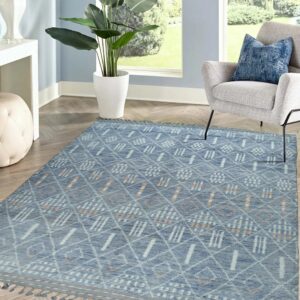 Blue geometric rug with light accents and tassels on herringbone wood flooring in a bright room.