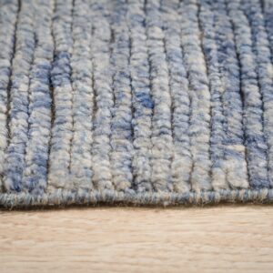 Textured blue and cream high pile rug with pronounced vertical rows rests on light wood grain.