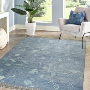 Blue geometric rug with fringe edges and abstract light blue shapes on herringbone wood floors.