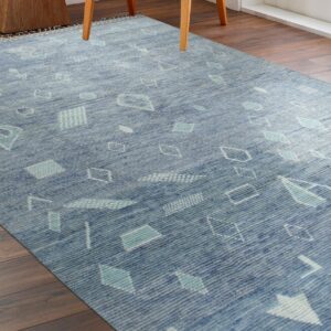 Textured blue rug with abstract turquoise and white geometric shapes rests on dark brown plank wood flooring.