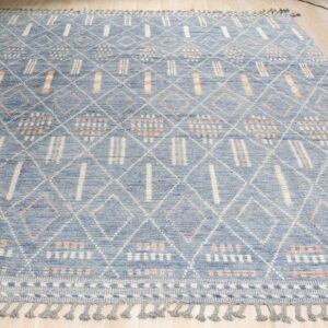 Textured blue rug featuring a white diamond lattice and orange accents, displayed on light wood flooring.