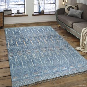 Blue geometric area rug with orange and white accents on a rustic wood floor near a gray sofa.