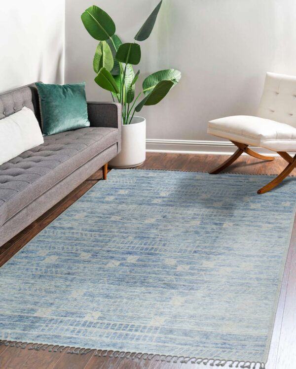 Variegated blue and beige patterned area rug grounds a living area with a gray couch and white accent chair.