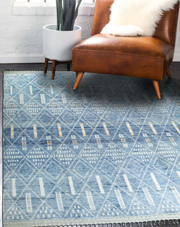 Blue textured rug with white and tan geometric patterns complements a distressed brown leather chair.