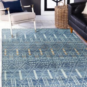 Blue geometric rug with white and orange accents covers tile floor near an armchair and black sofa.