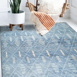 Blue rug with white and peach diamond and dash patterns anchors a bright corner with a potted plant and wicker chair.