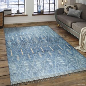 Blue textured rug with abstract white and peach geometric patterns on rustic wood floors.