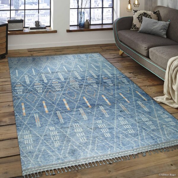 Blue textured rug with abstract white and peach geometric patterns on rustic wood floors.