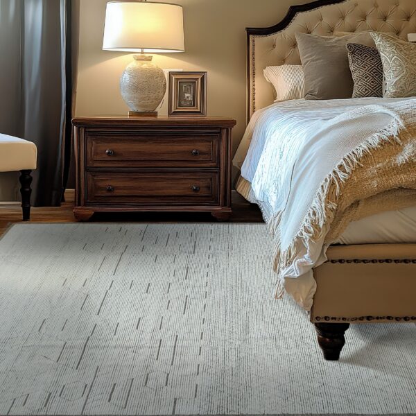 A ribbed gray rug with darker accent dashes sits on wood flooring beside a dark wood nightstand and upholstered bed.