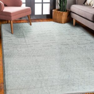 A textured pale gray rug with subtle geometric lines sits on wood floors between a pink chair and gray sofa.