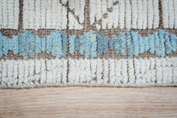 High-pile rug texture with abstract blue and cream bands resting on a light wooden surface.