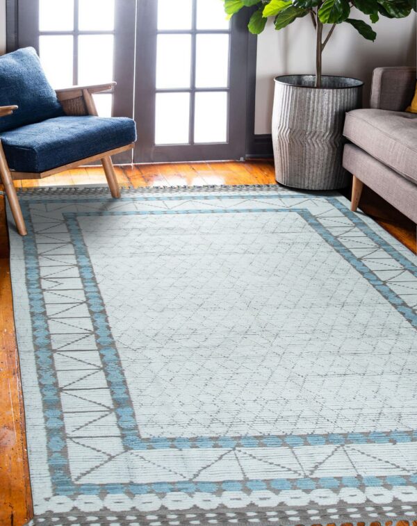 Light blue diamond-patterned rug with turquoise and gray borders on wood floors near furniture and a glass door.