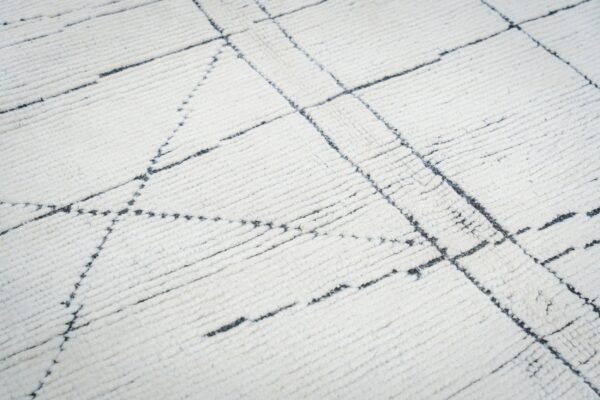 Close-up of a shaggy white rug featuring an irregular black geometric grid pattern.