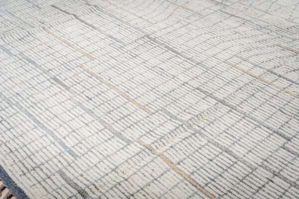 Cream high-pile rug texture with a geometric grid pattern in subtle gray, blue, and tan tones.