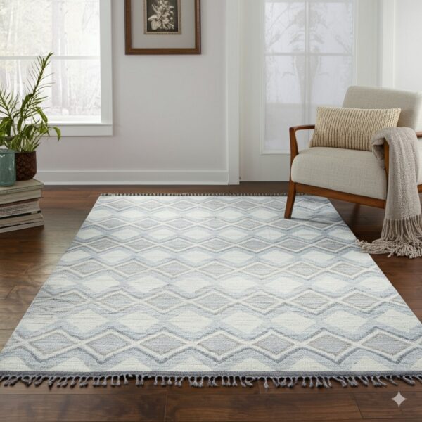 Light blue and gray diamond rug with fringe sits on dark wood floors near a cream armchair.