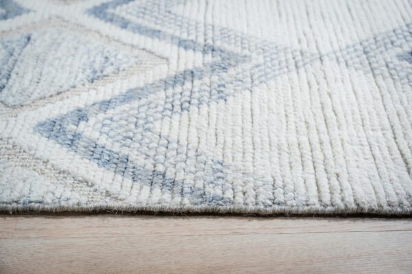 High-pile shag rug featuring a blue and white geometric design rests on light wooden floorboards.