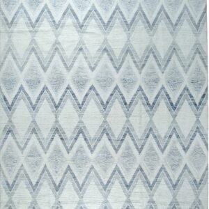 Textured white rug with blue and gray geometric zigzags and diamond patterns, detailed with fringe.
