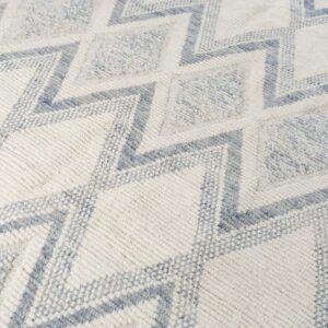Textured off-white rug with geometric dusty blue zigzag lines and diamond shapes.