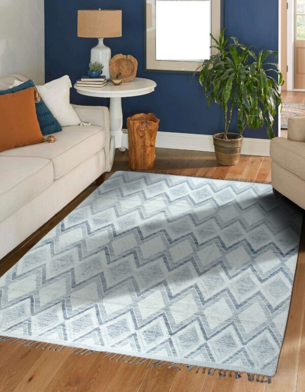 Low-pile white and blue rug featuring a textured zigzag pattern lies on wood floors in a living room.