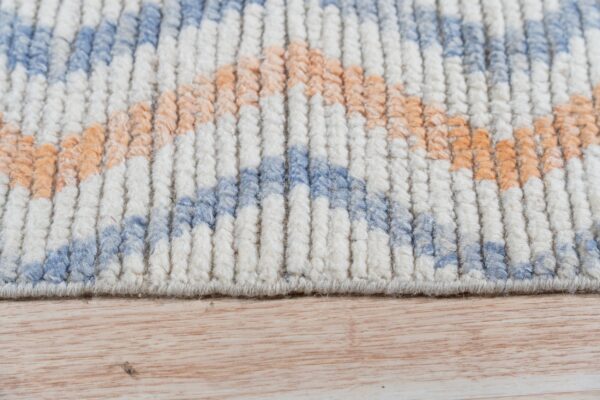 Chunky textured rug pile in off-white, light blue, and peach, resting on light wooden flooring.