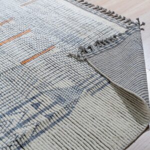 High-pile cream and blue ribbed rug with orange lines, showing the fringed backing on light wood flooring.