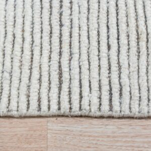 The high-pile, ivory-toned rug has vertical ribs and dark stripes, seen against light wood flooring.