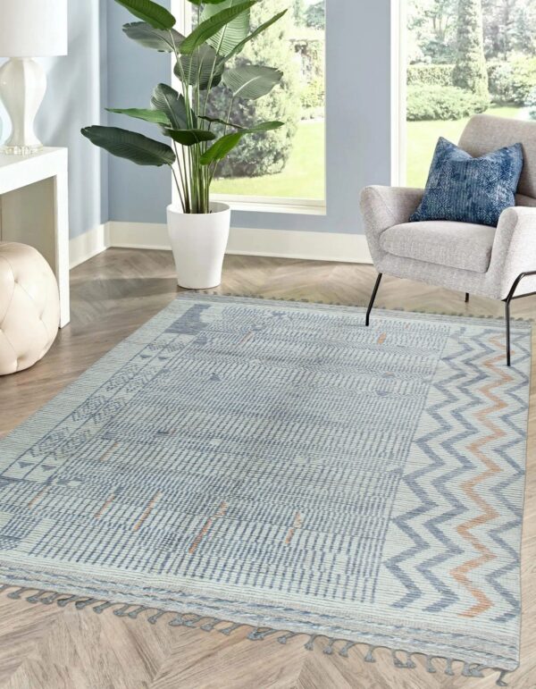 Light blue and cream low-pile rug with geometric and chevron patterns displayed on wood flooring.