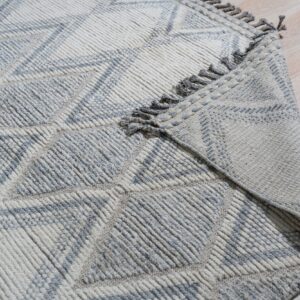 Textured cream and gray high-pile rug with geometric diamond pattern on light wood floors.