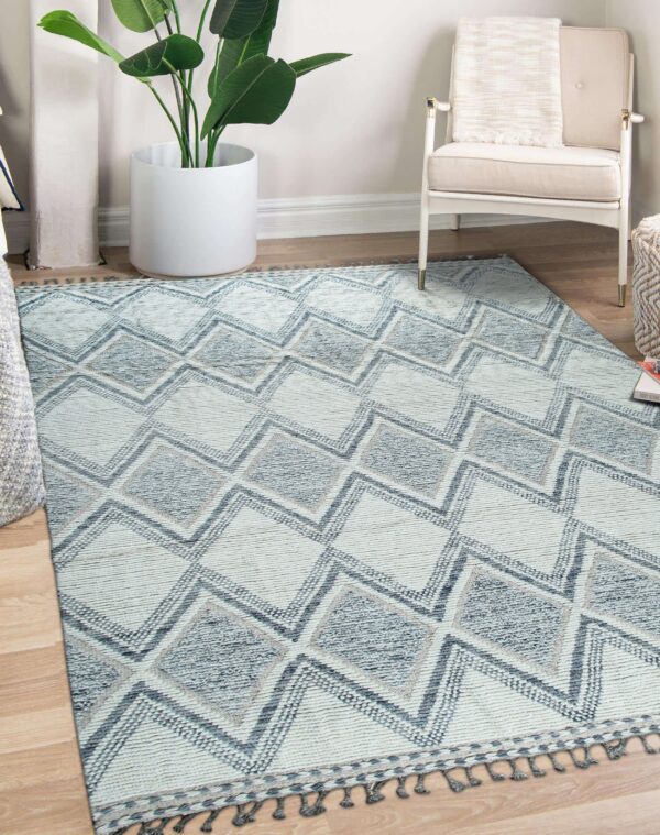 Textured rug with blue and cream geometric diamonds and tassels on light wood flooring.