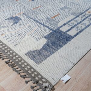 Chunky textured white rug featuring blue, gray, and subtle orange geometric patterns on light wood flooring.