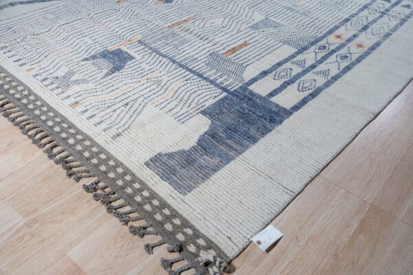 Chunky textured white rug featuring blue, gray, and subtle orange geometric patterns on light wood flooring.