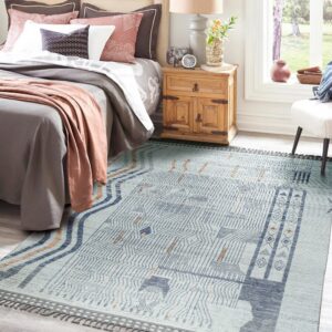 Pale blue geometric rug with dense indigo patterns and rust accents placed beside a wooden nightstand in a bedroom.