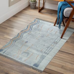 Low-pile rug with light blue, indigo, and orange abstract designs sits on wood plank flooring.