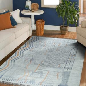A low-pile geometric rug in blue, off-white, and rust rests on wood flooring in a navy blue living room.