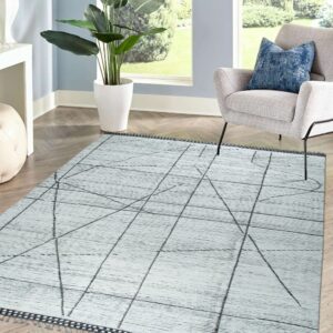 Light gray rug with black geometric lines and fringe sits beneath a gray chair on herringbone wood floors.